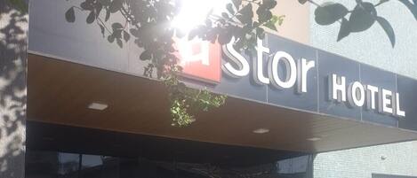 El exterior de un hotel con un letrero que dice "Stor Hotel". Hay plantas en macetas grandes frente a la entrada.