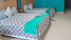 Ein Hotelzimmer mit zwei Betten, türkisfarbenen Wänden, einem Bild an der Wand und einer Klimaanlage.