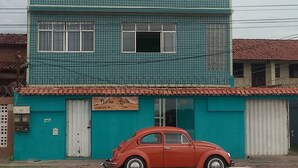 Ein zweistöckiges Gebäude mit blauer Fassade und einem roten Auto davor.
