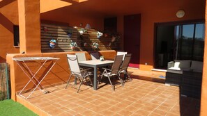 Eine Terrasse im Freien mit Tisch und Stühlen, einer Wäscheleine und einer mit Topfpflanzen bepflanzten Wand.