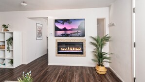 Una sala de estar moderna con chimenea, televisor montado y estantería.
