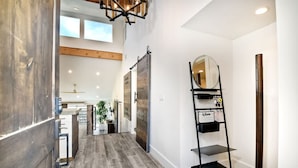 Un intérieur moderne avec un plancher en bois, une porte coulissante de style grange, une étagère en métal noir avec un miroir et un ventilateur de plafond.
