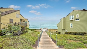 Un sentier qui mène à une plage, avec deux maisons de chaque côté.
