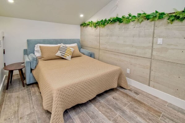 A bedroom with a bed, a small side table, and a headboard with greenery. - Sea Bluff - Direct Beach Access (Encinitas)