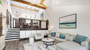 Un salon moderne avec un canapé, une table basse et un escalier menant à une cuisine.