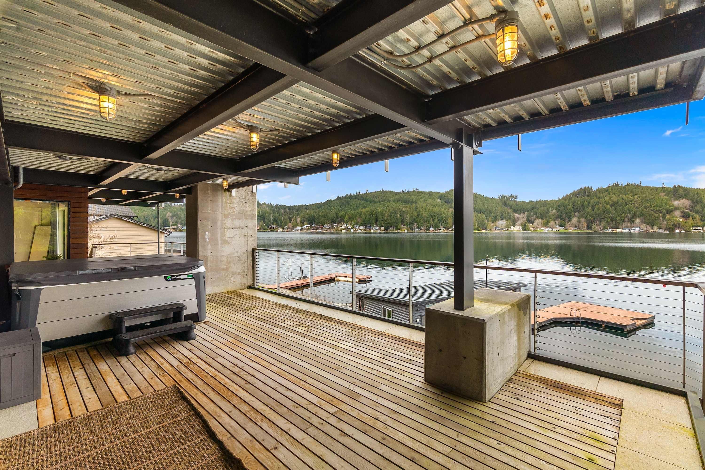 A covered deck with a grill, a view of a lake, and a dock.