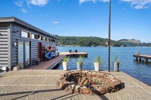 Una cabaña junto al lago con muelle, asientos exteriores y una zona para fogata.