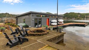 Un chalet au bord du lac, doté d’un quai, d’un espace salon extérieur et d’un foyer en pierre.