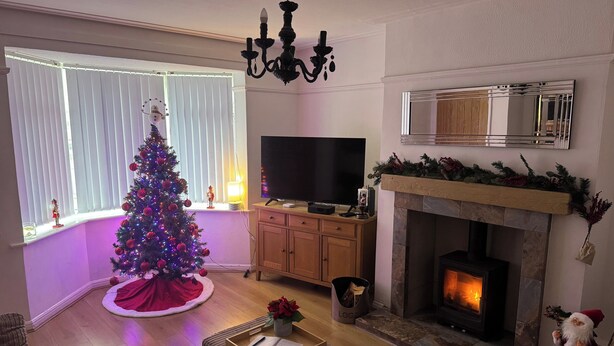 A cozy living room with a fireplace, a Christmas tree, and a television.