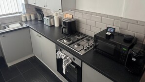A modern kitchen with a gas stove, a microwave, a toaster, and a coffee maker.