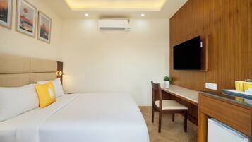 Ein Hotelzimmer mit Bett, Schreibtisch, Sessel, Fernseher und Klimaanlage.
