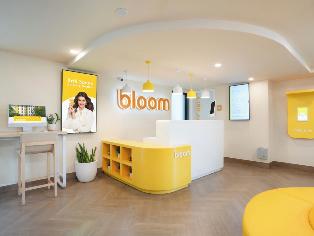 A reception area with a yellow and white color scheme, a reception desk, a computer, and a plant.