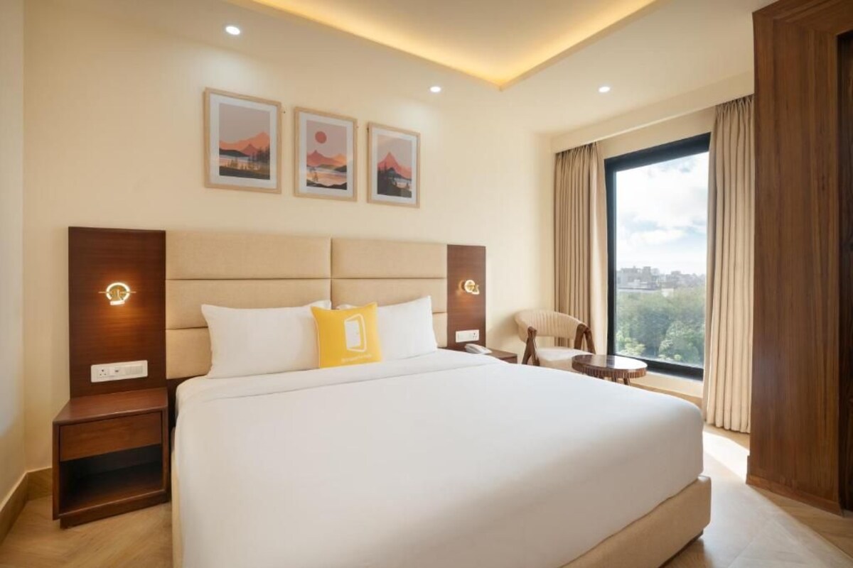 A large bed with a headboard, bedside tables, and a view of the city through a large window.