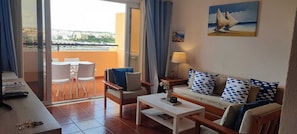 Relax in this open-plan living area with a sofa, coffee table, and balcony access.