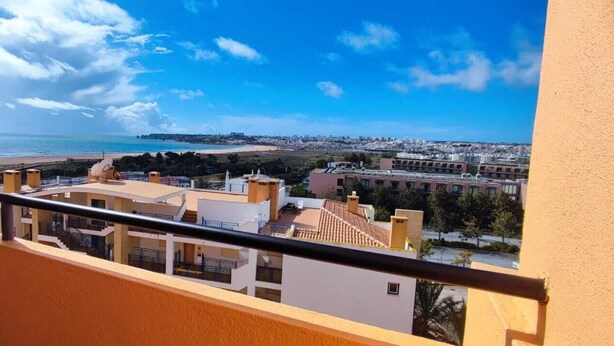 A balcony with a view of the beach and cityscape.