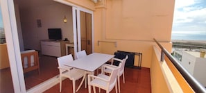 Enjoy the beach view from this room's balcony, featuring a table and chairs, a heater, and a TV.