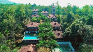 A resort with multiple bungalow-style buildings, a swimming pool, and lush greenery surrounding the property. - The Wave Wayanad Resort (Sulthan Bathery)
