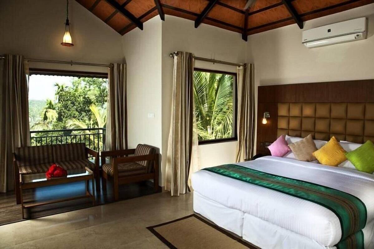 A hotel room with a bed, a sofa, and a window with curtains.
