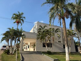 A modern building with a flat roof, surrounded by palm trees.