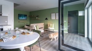Una cocina moderna con armarios blancos, una mesa de comedor dispuesta con platos y vasos, y una pared verde con obras de arte.