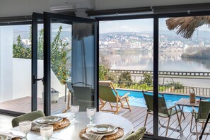A dining area with a table set for four, overlooking a swimming pool and a cityscape. - Feel Discovery Casa D'Alice (Peso da Régua)