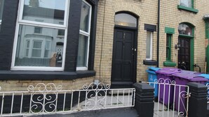 A corner of a building with a black door, a window with a white frame, and a metal fence with decorative elements. - Sefton House by Smart Corporate Stays (Liverpool)