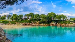 Una zona costera con mar azul cristalino, costa rocosa y edificios con balcones con vistas al agua.