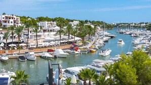 Un puerto deportivo con numerosas embarcaciones amarradas, rodeado de edificios y palmeras.
