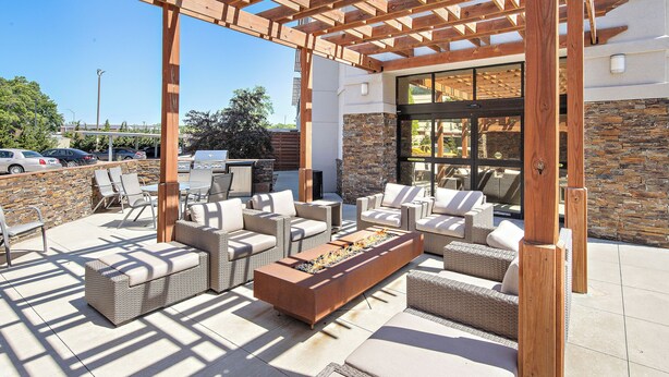 Un patio exterior con mobiliario de mimbre, una chimenea y una pérgola.