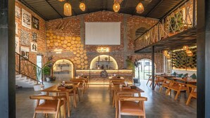 Ein Restaurant mit Backsteinwänden, Holztischen und hängenden Lampen.
