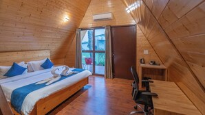 Ein Zimmer mit Holzboden, einem Bett, einem Schreibtisch und Blick durch eine Glastür.