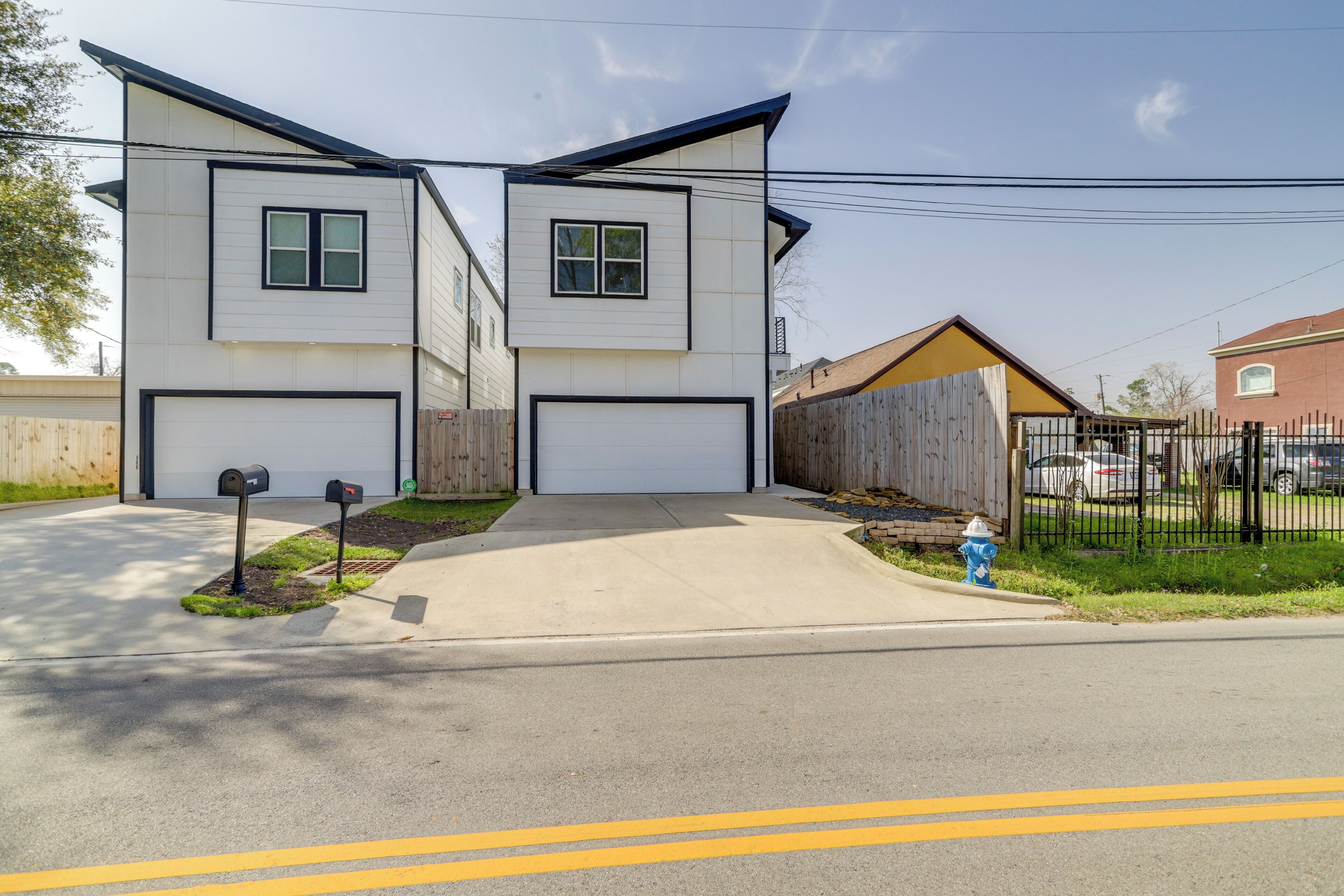 A two-story residential building with a garage, a driveway, and a fenced yard.