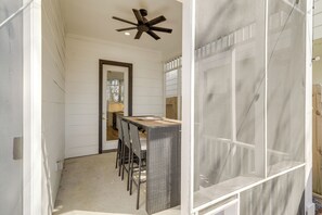 A compact kitchen with white paneling, a wooden dining table, and a ceiling fan. - Sleek Home w/ Screened Patio & Yard in Houston! (Houston)