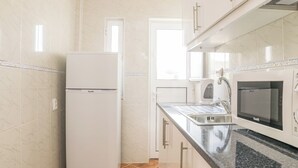A kitchen with white cabinets, a built-in microwave, and a stainless steel sink. - Spyro Red Villa, Lagos, Algarve (Lagos)