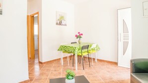 A dining area with a table covered in a green tablecloth, surrounded by white chairs. There is a vase with pink flowers on the table. - Spyro Red Villa, Lagos, Algarve (Lagos)