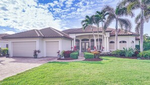 A residential house with a tiled roof, a garage, and a well-maintained lawn with various plants and flowers. - 3 Mi to Bonita Beach: Outdoor Oasis w/ Pool & Spa! (Bonita Springs)