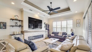 A modern living room with a fireplace, leather sofas, a flat-screen TV, and a ceiling fan. - 3 Mi to Bonita Beach: Outdoor Oasis w/ Pool & Spa! (Bonita Springs)