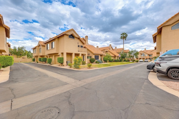 A residential street with houses, a clear sky, and parked cars.