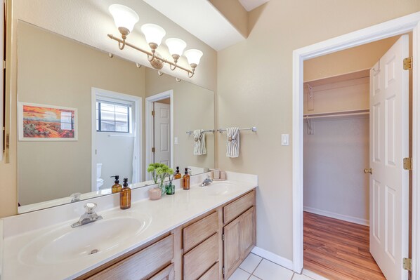 Une salle de bain avec un double vasque, un grand miroir et un dressing.