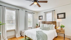 A bedroom with a wooden bed, two bedside tables, a ceiling fan, and a green rug. - Walk to Amphitheater & Stadium: Home w/ Deck! (Birmingham)