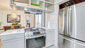 A modern kitchen with white cabinetry, a stainless steel refrigerator, a built-in oven, and a gas stove. - Walk to Amphitheater & Stadium: Home w/ Deck! (Birmingham)