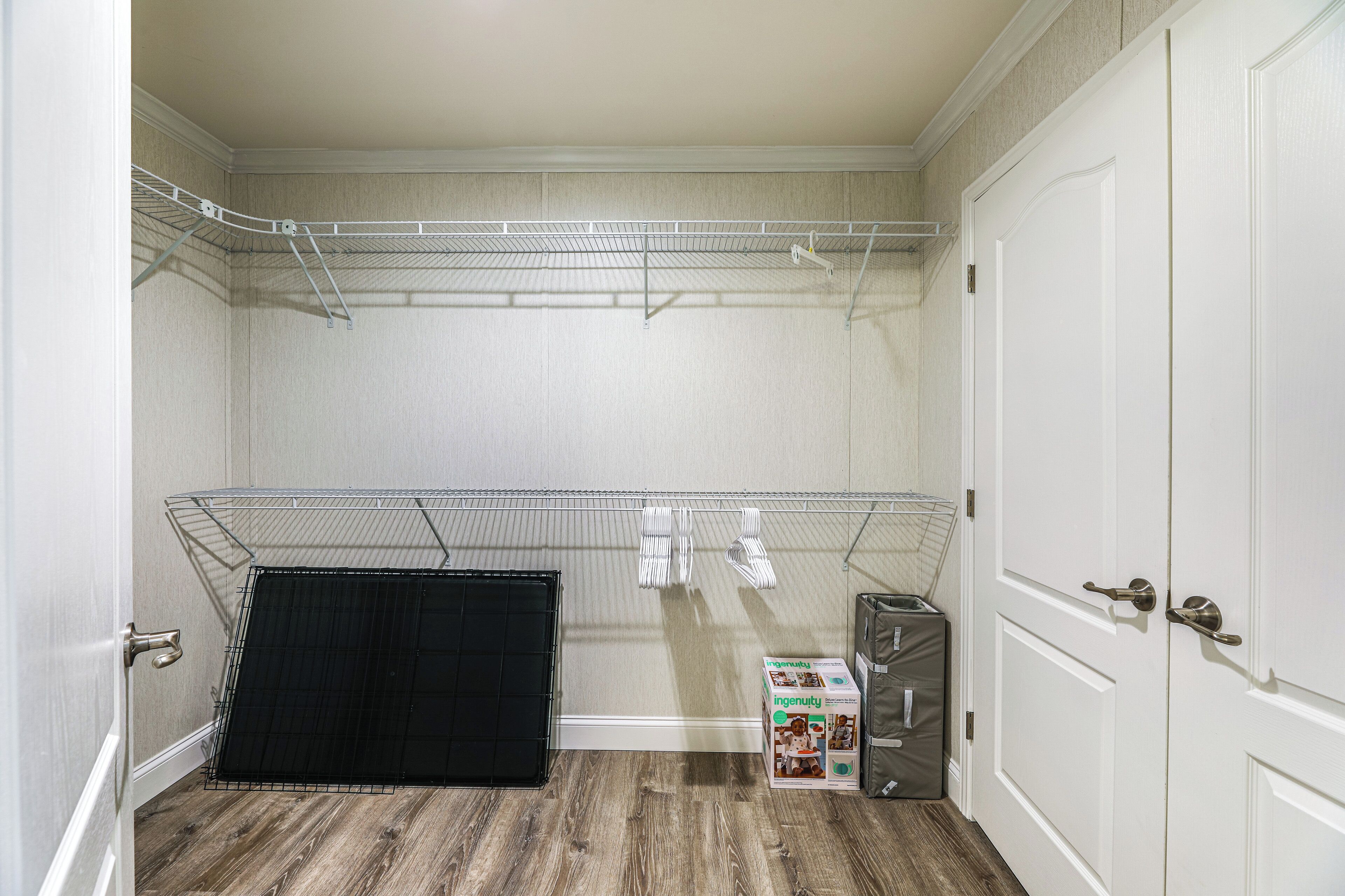 A room with a metal shelving unit, a black curtain, and a box labeled 'ingenuty'.