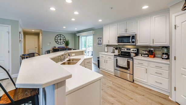 Una cocina moderna con armarios blancos, electrodomésticos de acero inoxidable y una isla central.