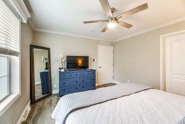 Un dormitorio con cama, cómoda, televisor, ventilador de techo y una puerta.