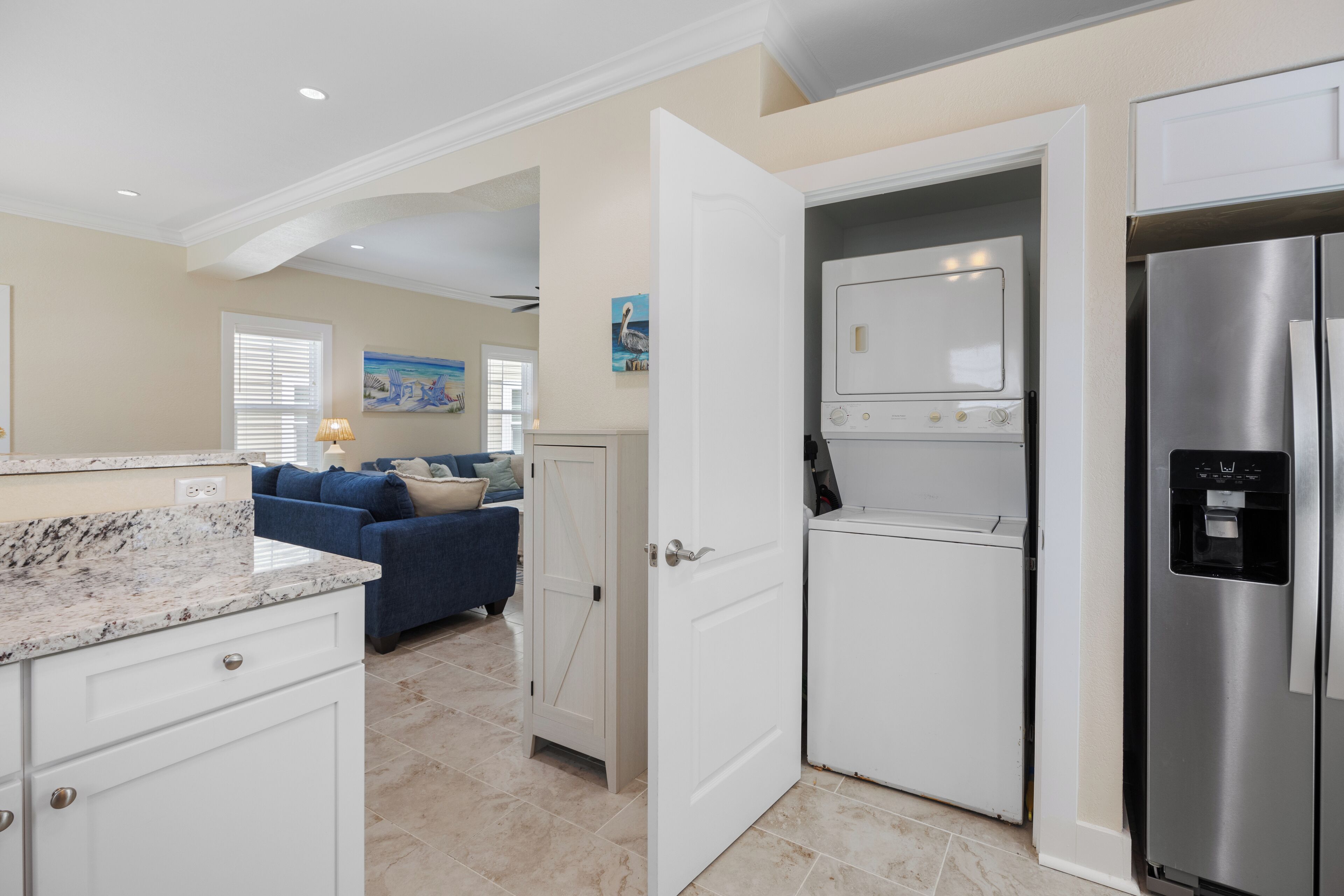 A kitchen with a stainless steel refrigerator, a built-in oven, and a microwave. There is a white door leading to another room.
