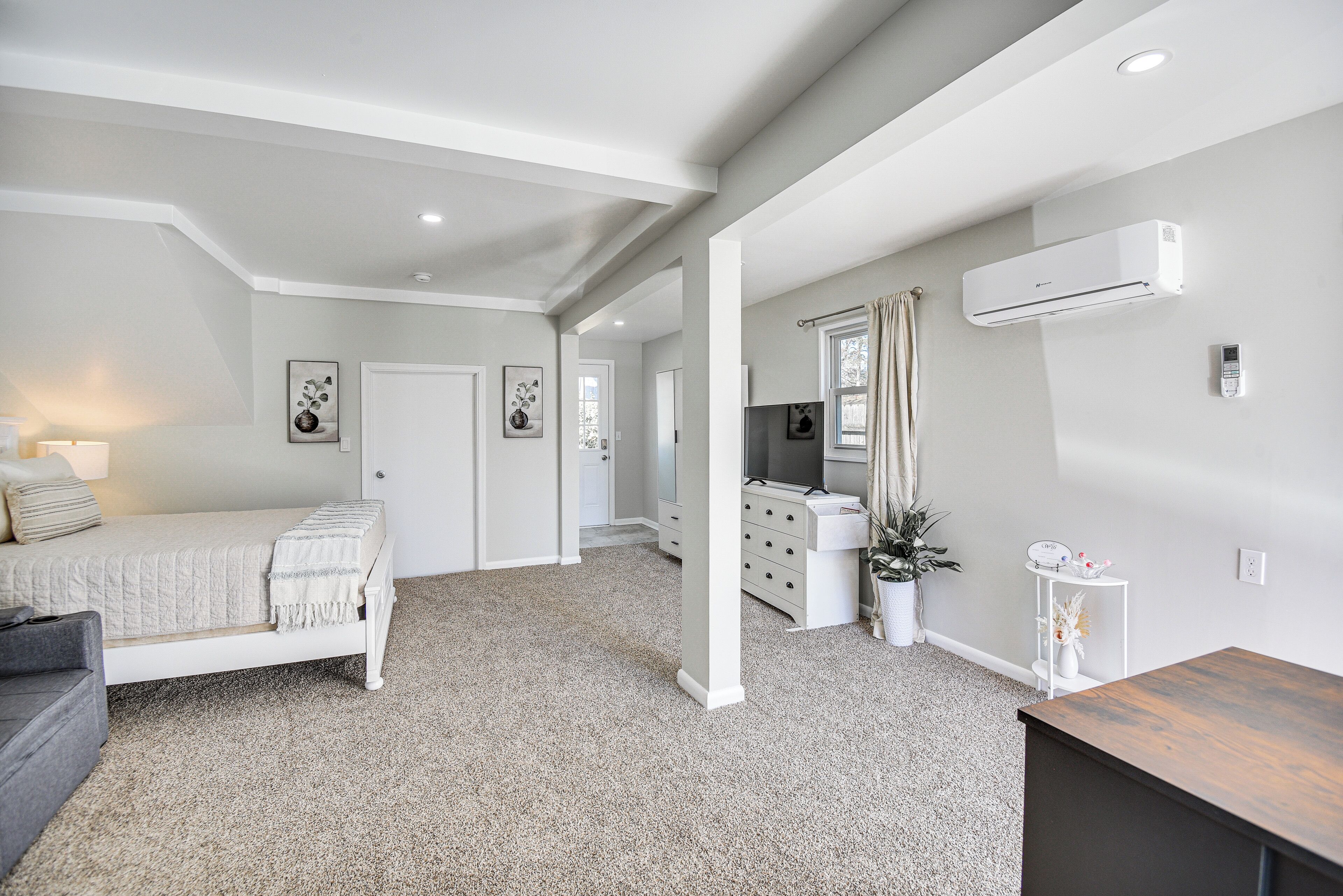 A spacious bedroom with a bed, a dresser, and a desk.
