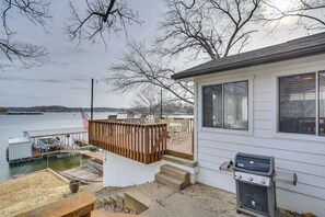 A waterfront property with a deck, outdoor seating, and a grill. - Sunrise Beach Lake House w/ Water Views & Dock! (Sunrise Beach)