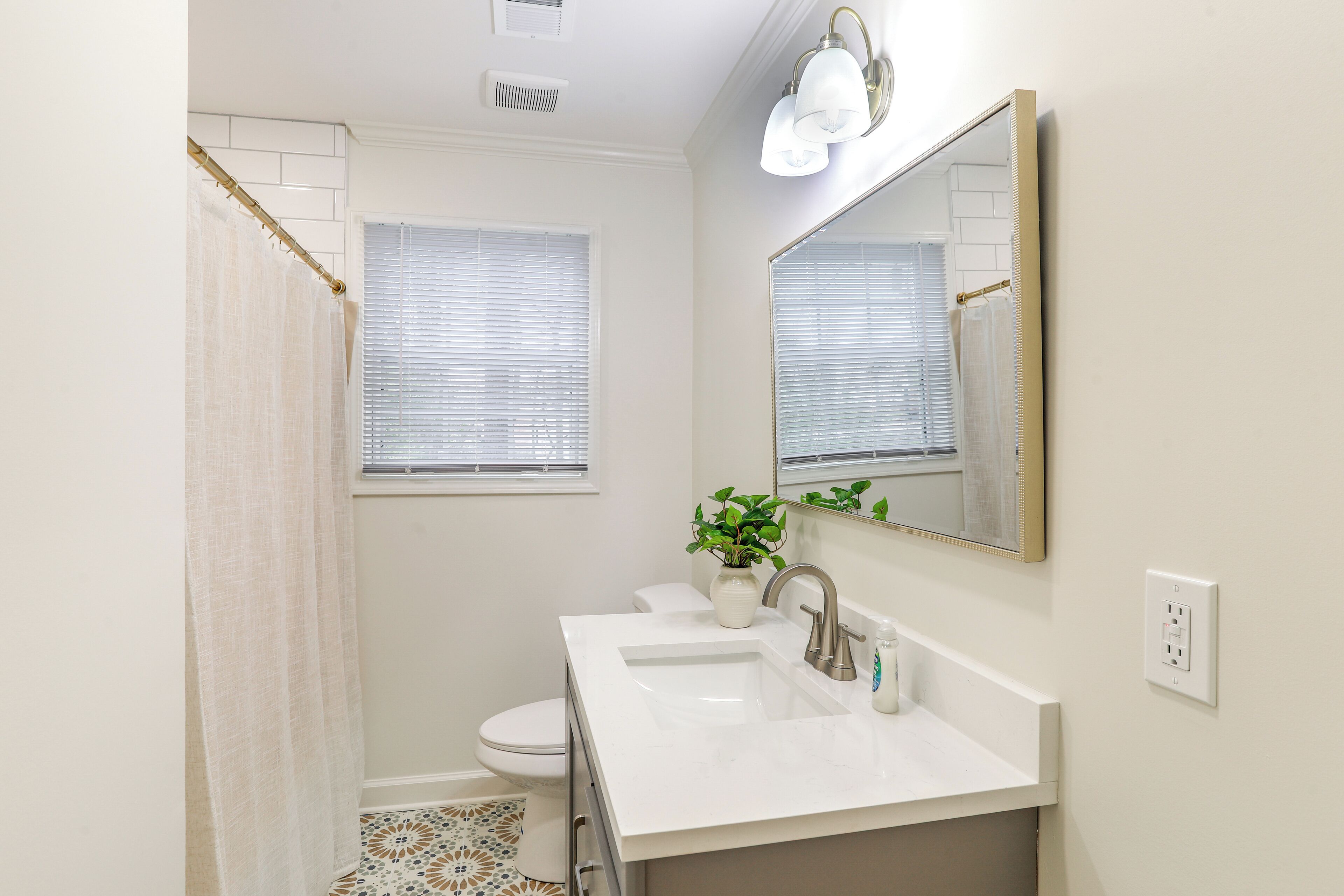 A bathroom with a white sink, a mirror, a toilet, and a shower curtain.