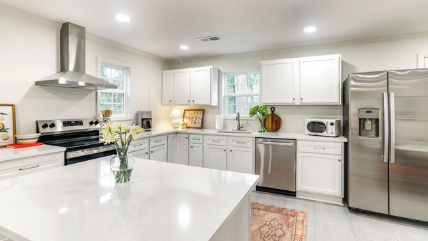 A modern kitchen with white cabinets, stainless steel appliances, and a central island.