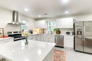 Una cocina moderna con armarios blancos, electrodomésticos de acero inoxidable y una isla central.